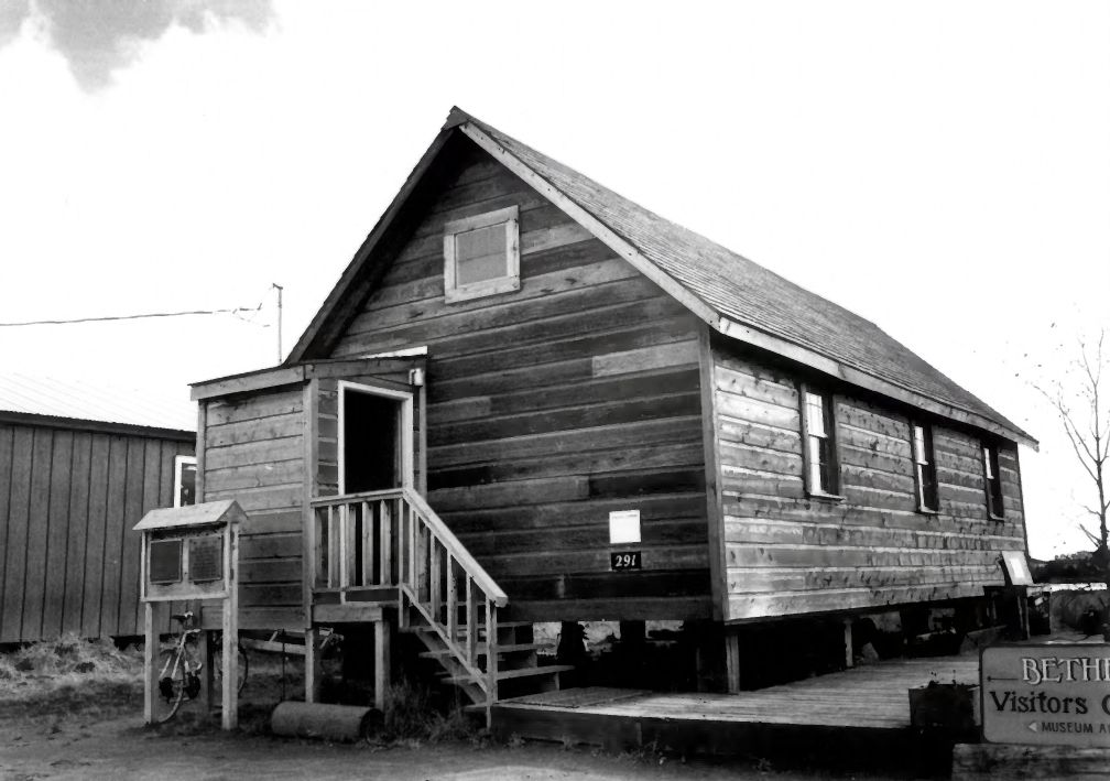Black and white photo of the First Mission House in Bethel, a small wooden building raised on posts with a front stair
