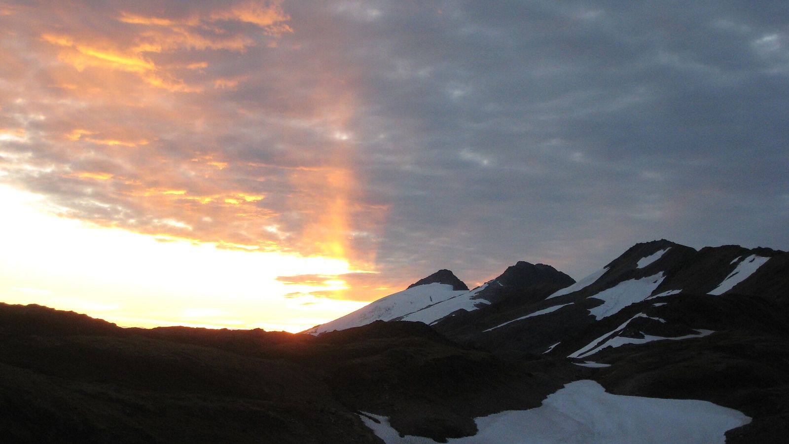 Sunrise breaking through clouds over the mountains of the Juneau Ridge