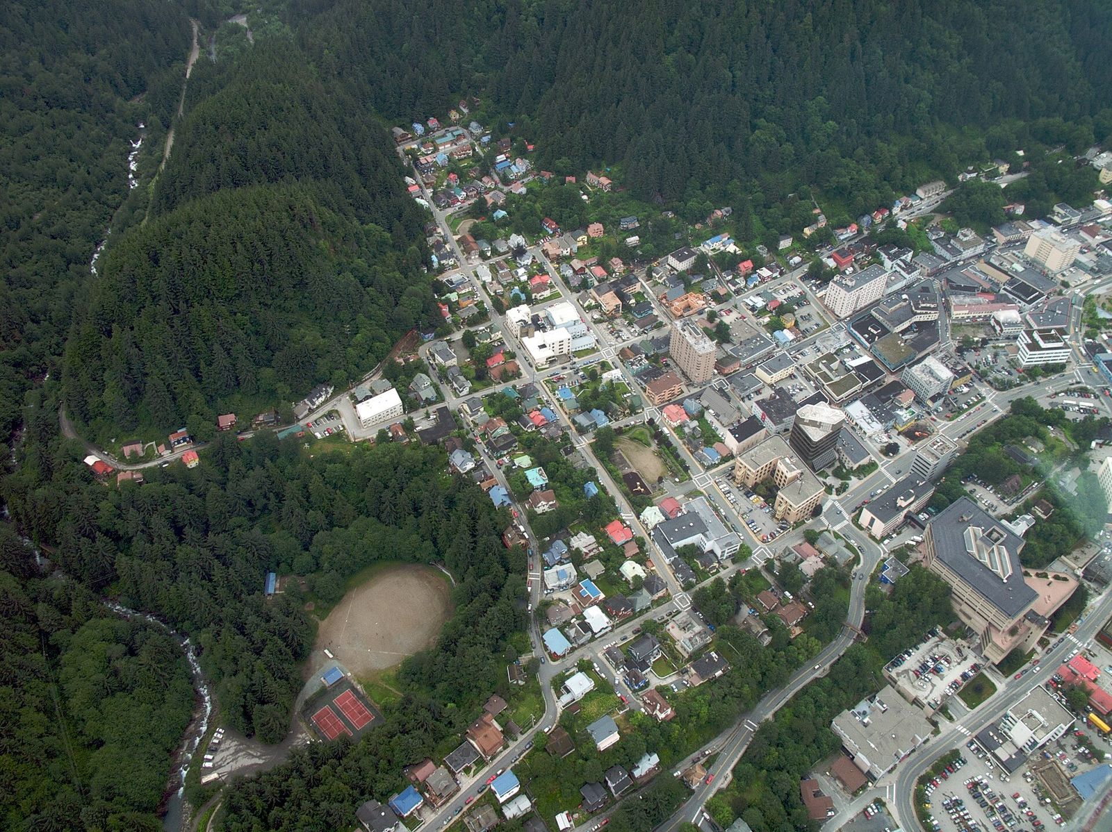 Aerial view of the streets and buildings of Juneau set against forested mountain slopes