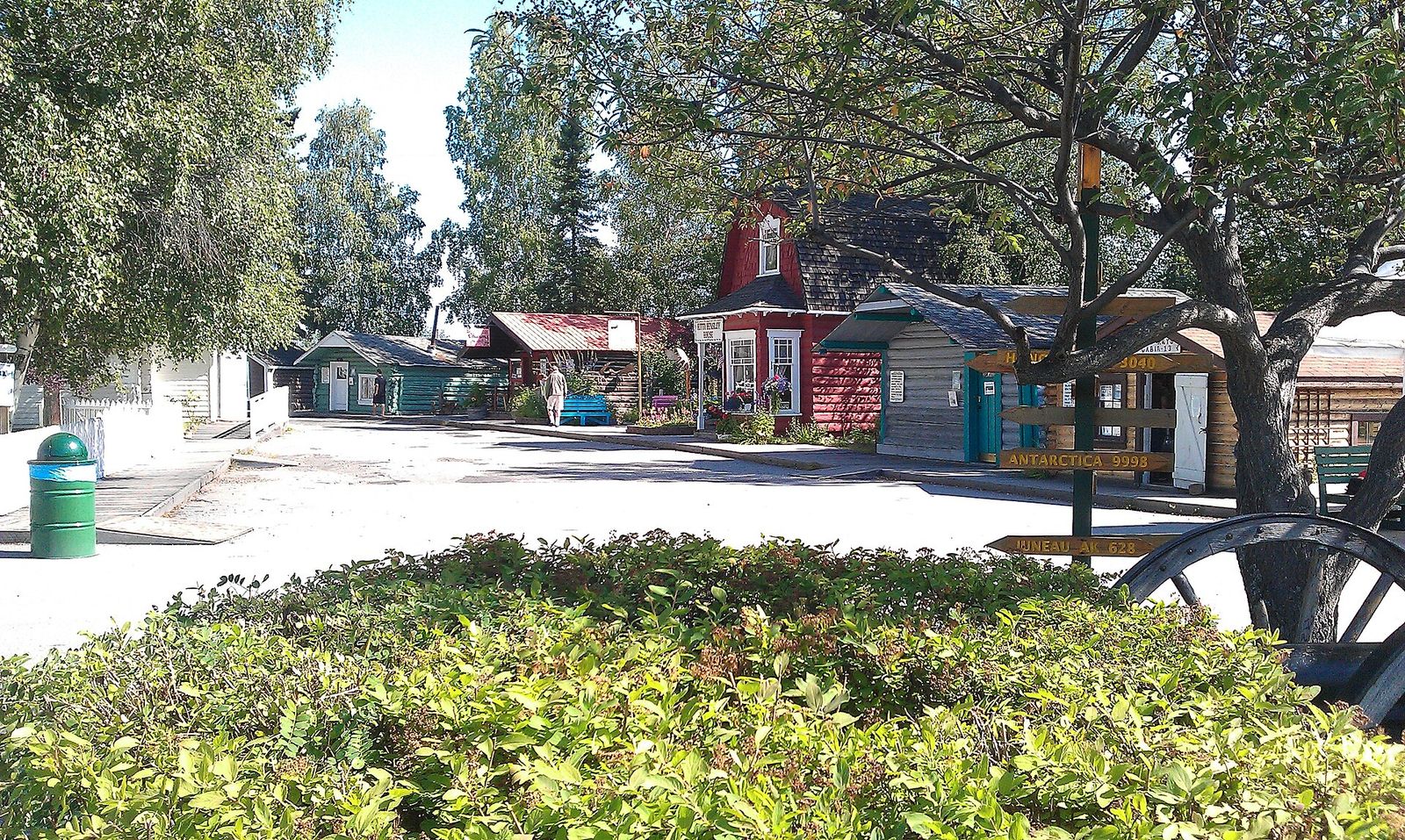Old wooden buildings moved to Gold Rush Town in Pioneer Park, Fairbanks, behind a bed of green plants