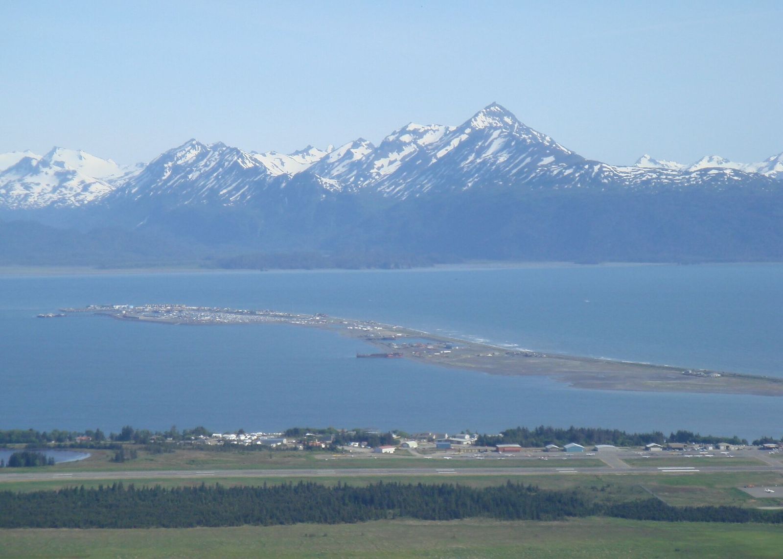 Aerial view of the Homer Spit reaching into Kachemak Bay below snowy mountains