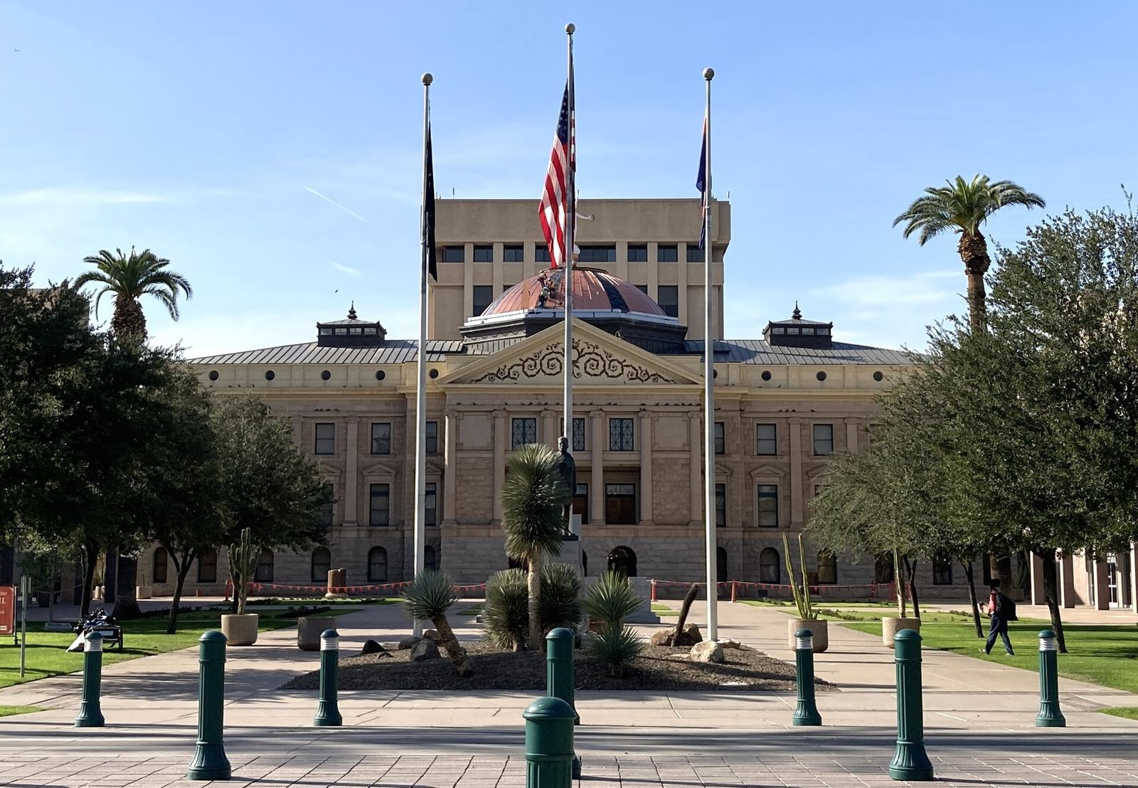 The Arizona State Capitol in Phoenix seen from the plaza, with flagpoles and palm trees in front