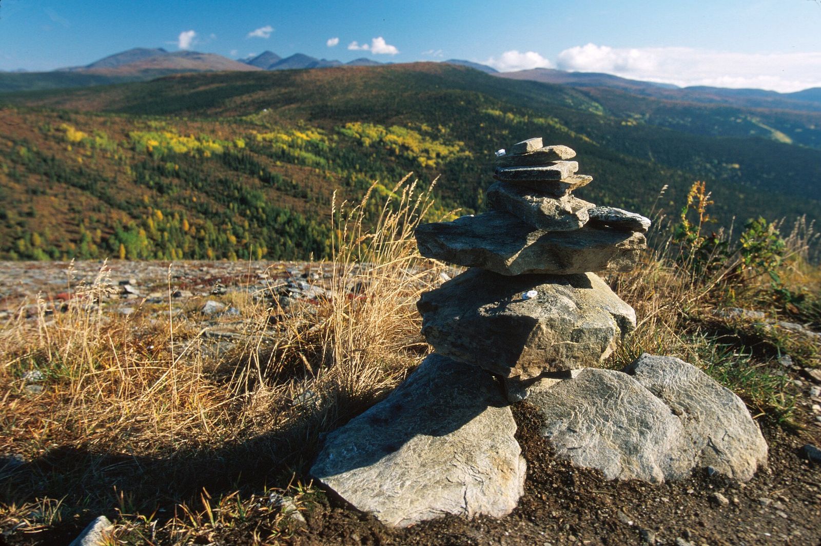 A rock cairn marking a hiking trail along an open ridge