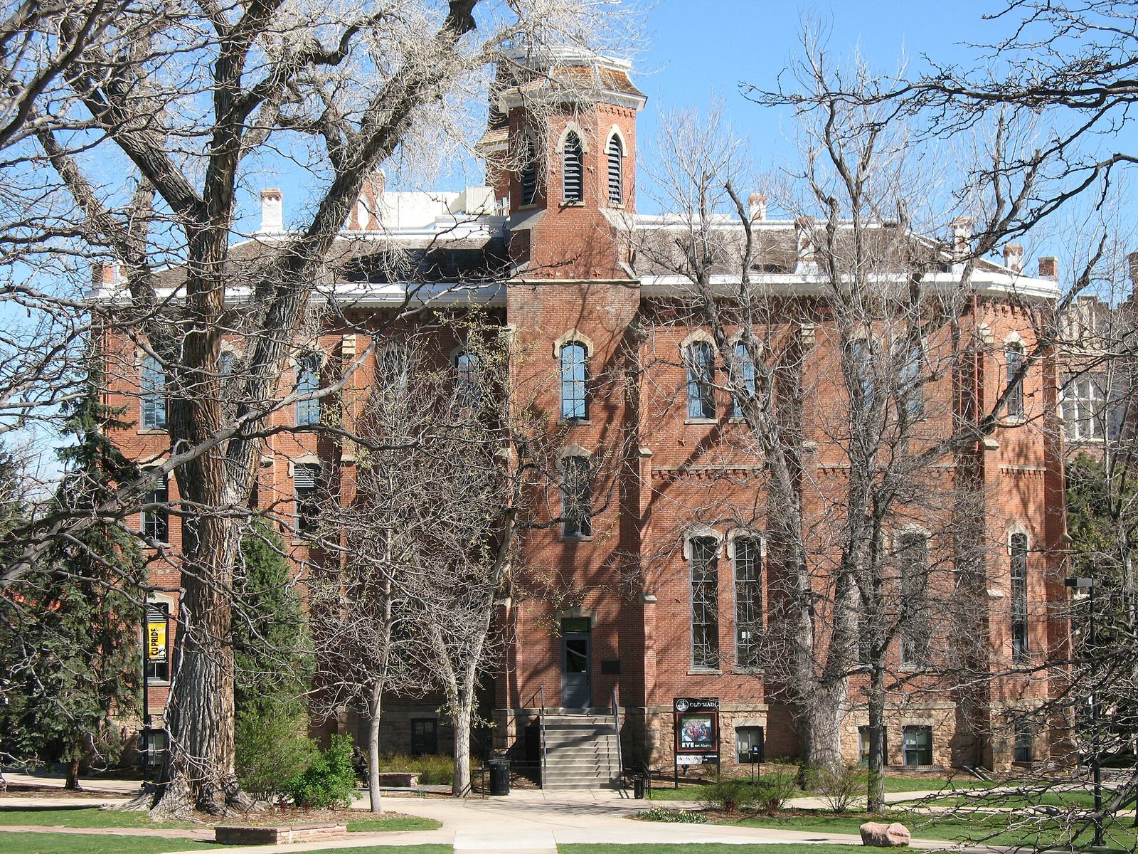 Old Main, the red brick hall on the University of Colorado Boulder campus, framed by bare trees