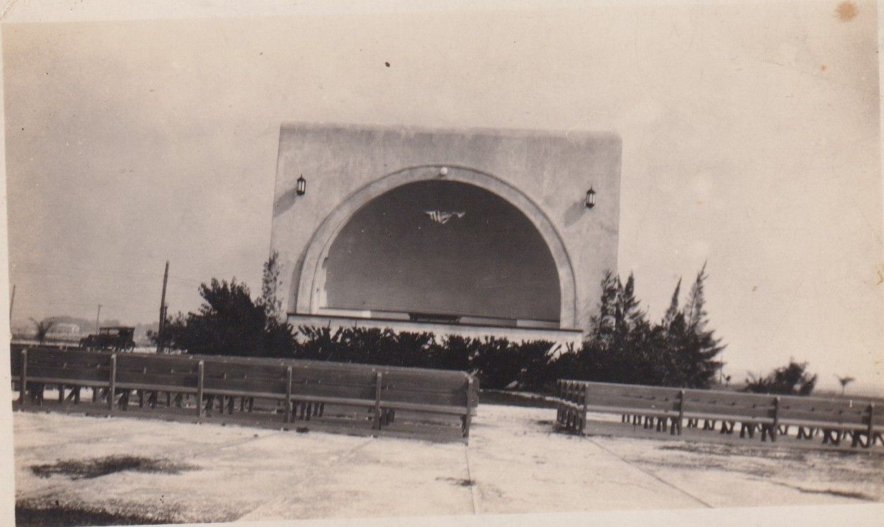 A sepia photograph from about the 1950s of the arched bandshell on Kissimmee's lakefront, with benches in front
