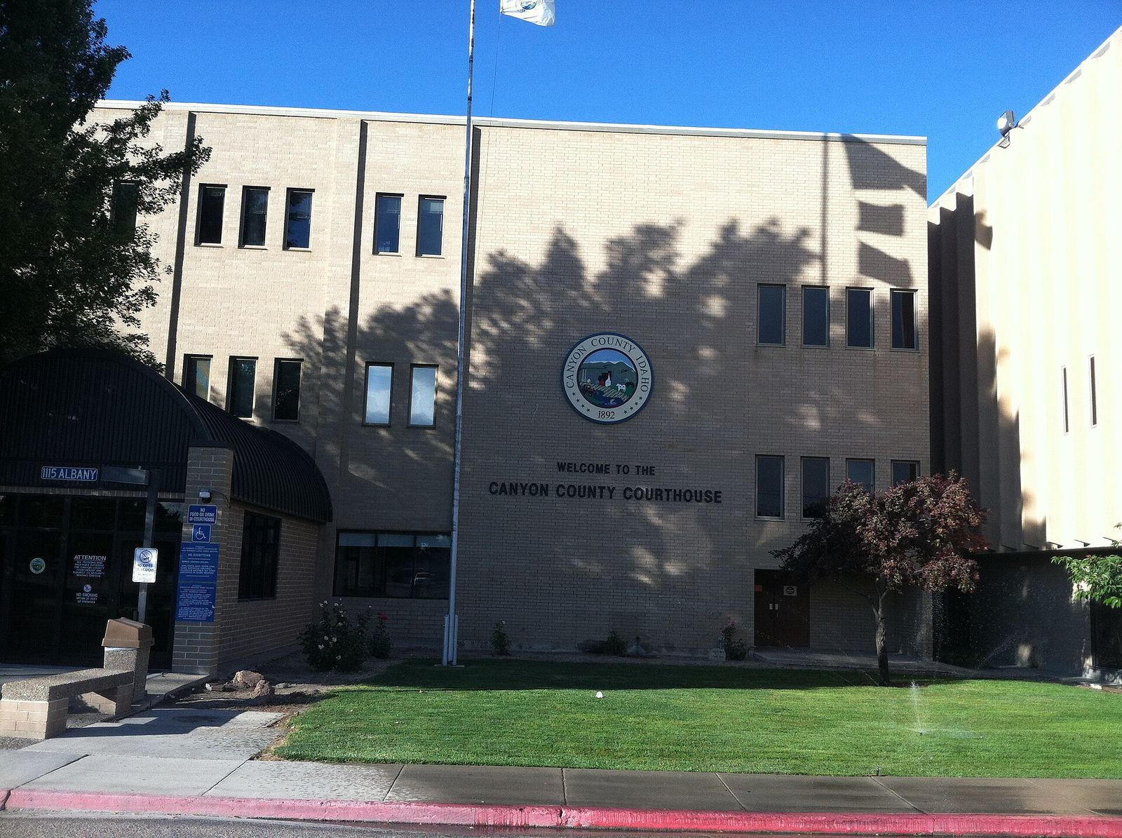 The Canyon County Courthouse in Caldwell, a tan multi-story building with the county seal over a green lawn