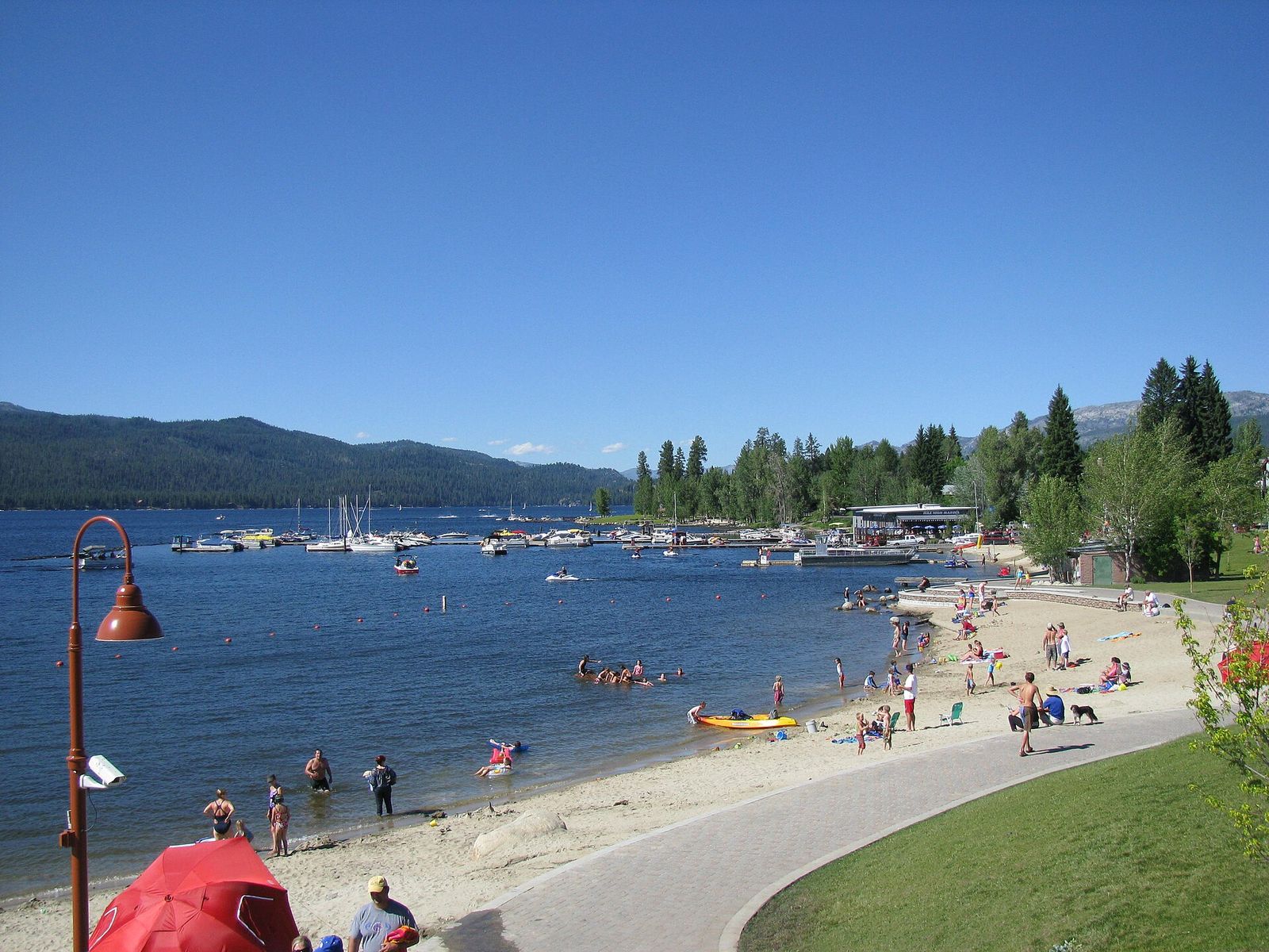 A summer beach and marina on Payette Lake in McCall, with forested mountains across the water