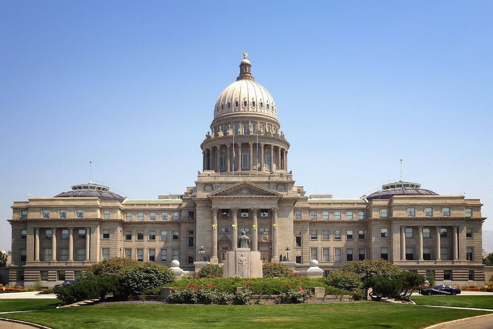 The Idaho State Capitol in Boise, a domed sandstone building, seen across its front lawn on a clear day