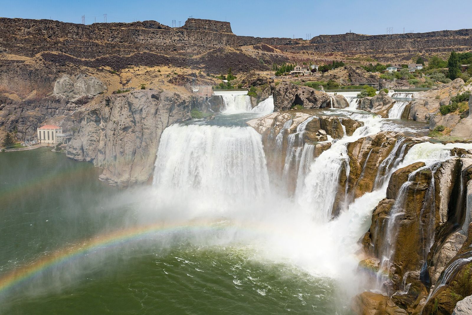 Shoshone Falls pouring over a wide basalt rim on the Snake River, with a rainbow in the mist below