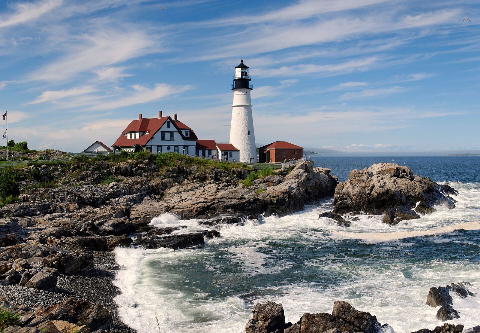 Portland Head Light and its red-roofed keeper's house on the rocky shore of Cape Elizabeth, with surf breaking below
