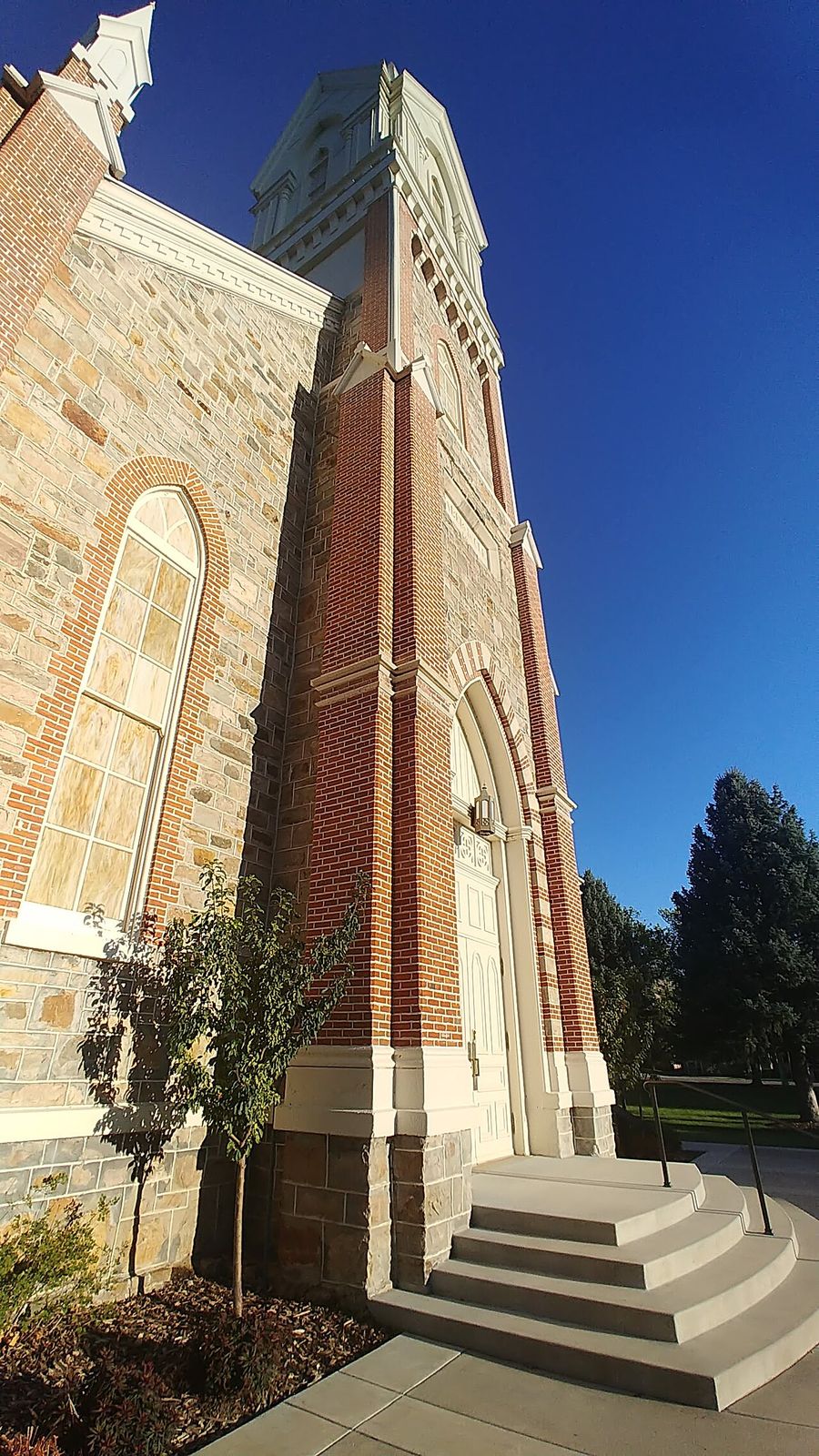 The stone Brigham City Tabernacle and its tall brick and stone tower against a blue sky