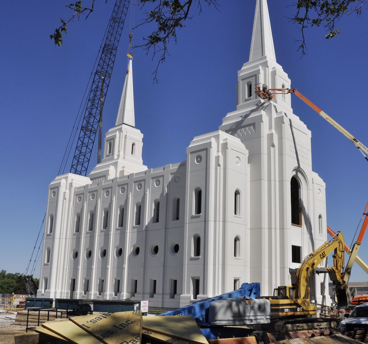 The white Brigham City Utah Temple under construction, with a crane and equipment beside it