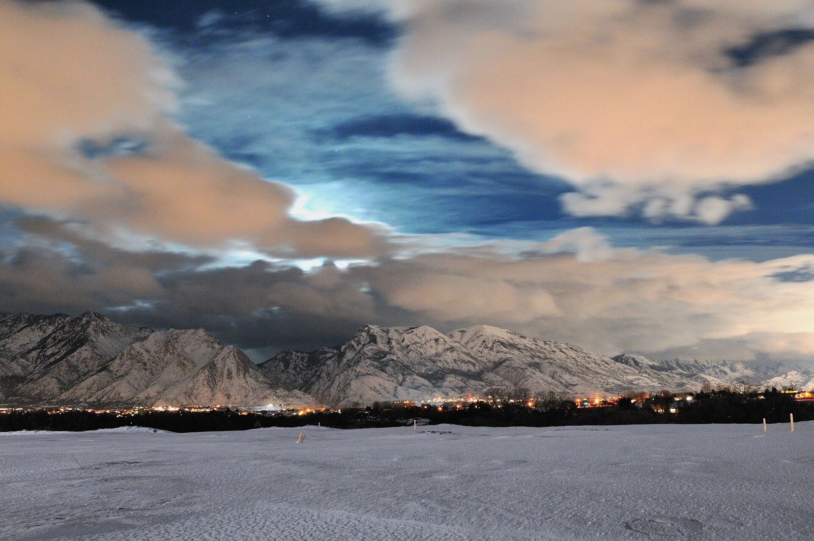A long night exposure over Highland, with snowy mountains, city lights and moonlit clouds