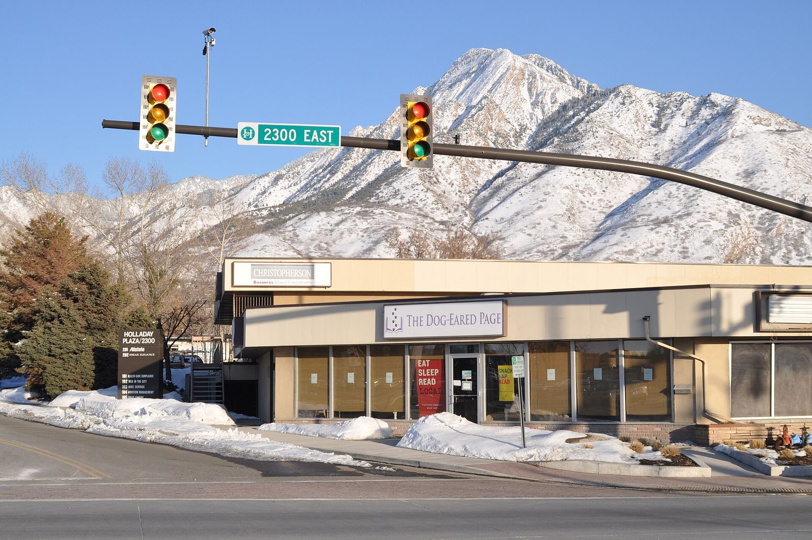 A low storefront at a 2300 East intersection in Holladay, with snowy Mount Olympus rising behind it