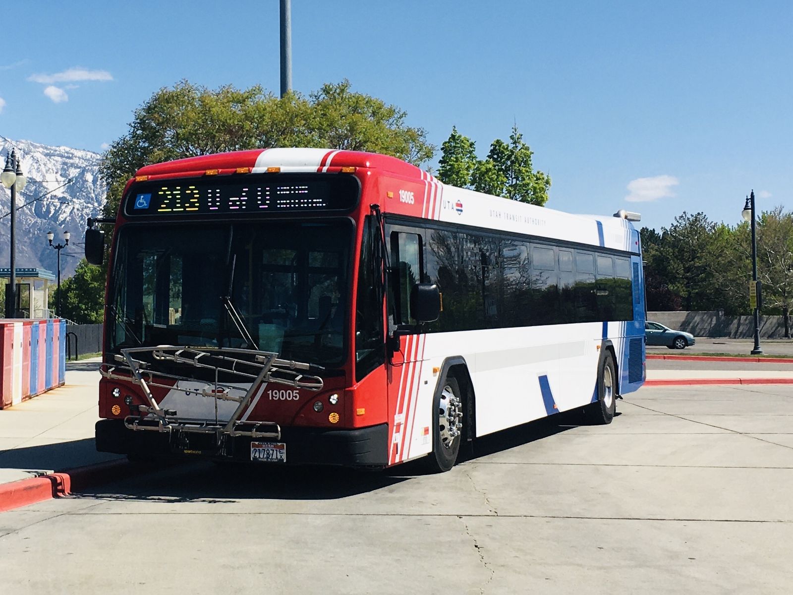 A red and white UTA bus waiting at Midvale Center station