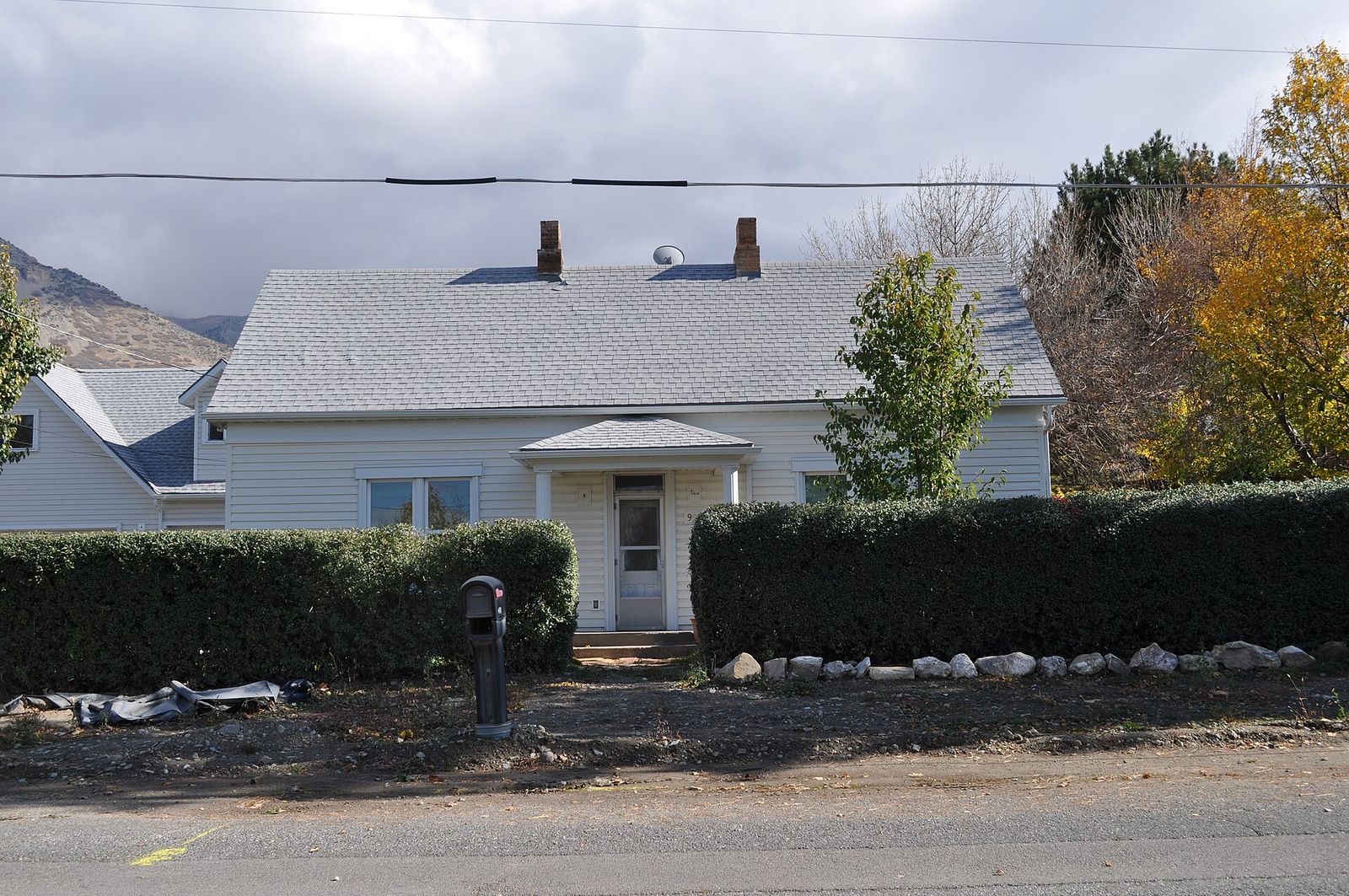 The historic Christen Larsen House in Pleasant Grove, a white home behind a hedge