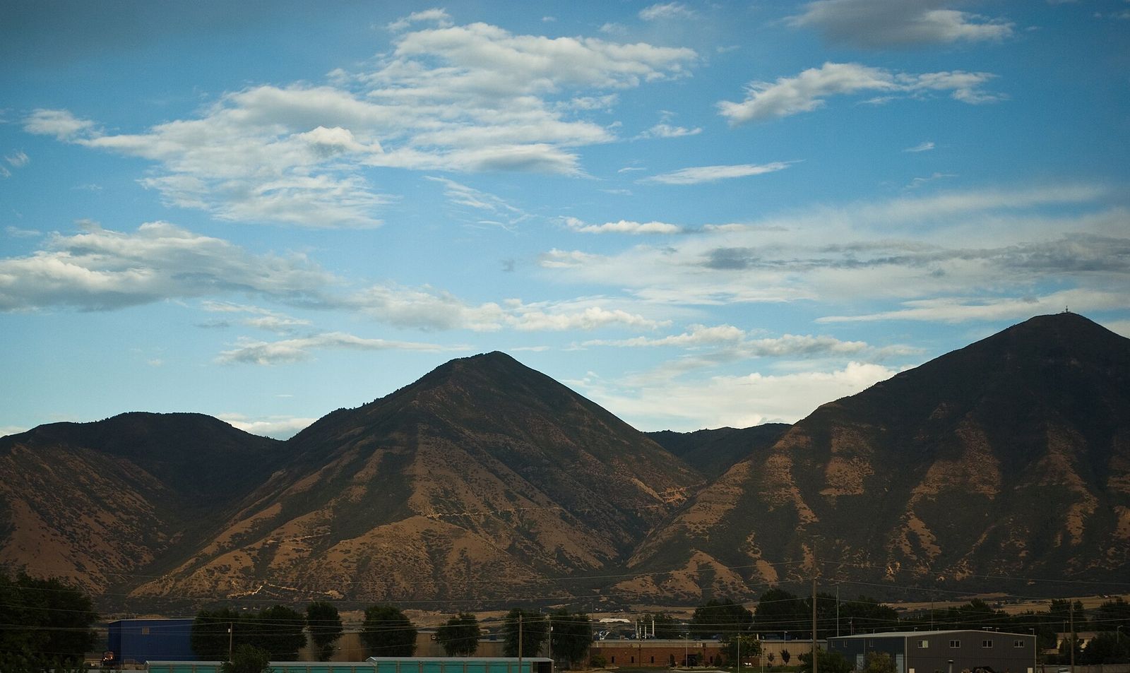 The brown ridges of Santaquin Peak and Dry Mountain under a blue sky with scattered clouds