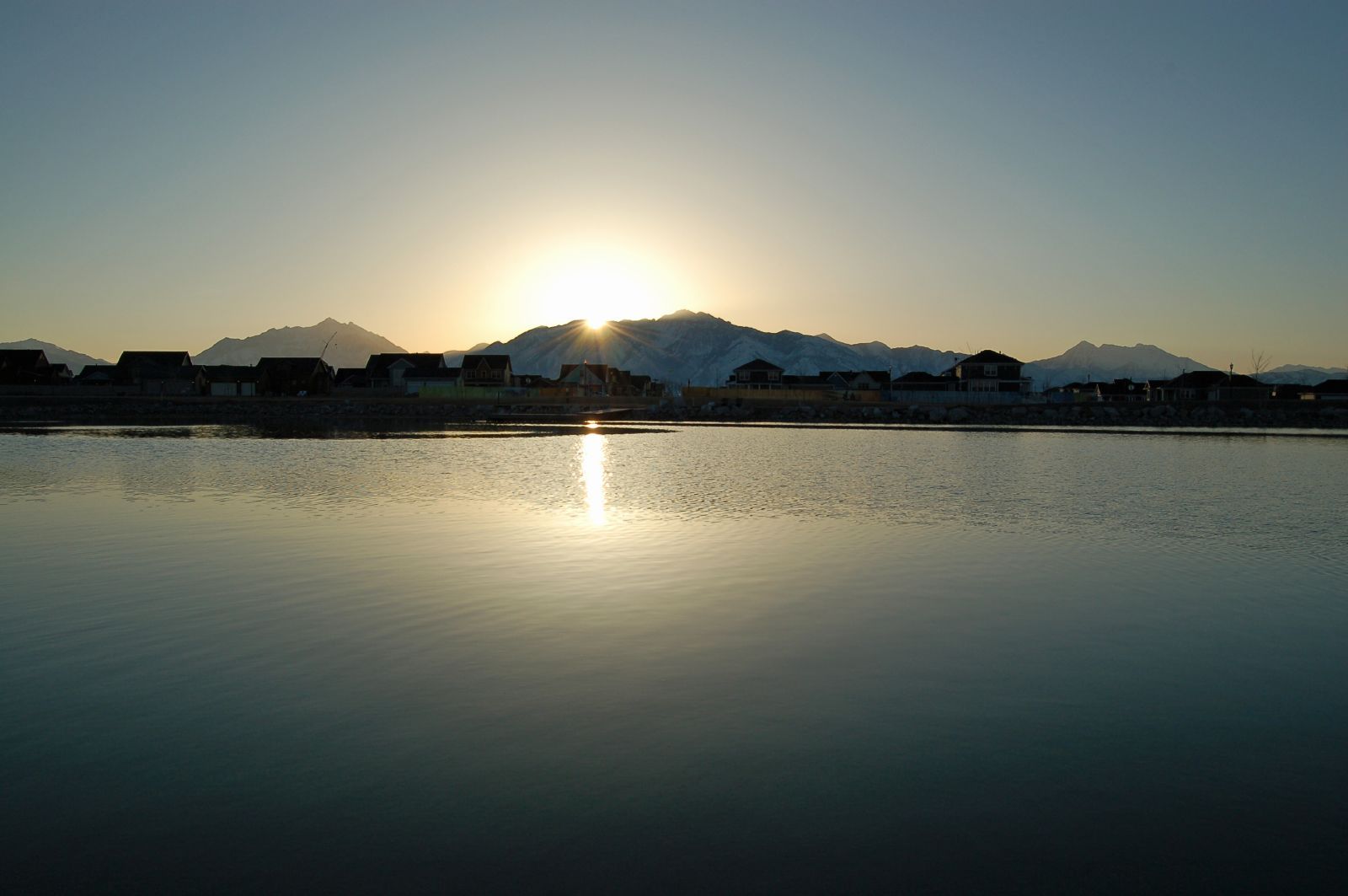 The sun rising over the Wasatch Mountains, reflected in Oquirrh Lake