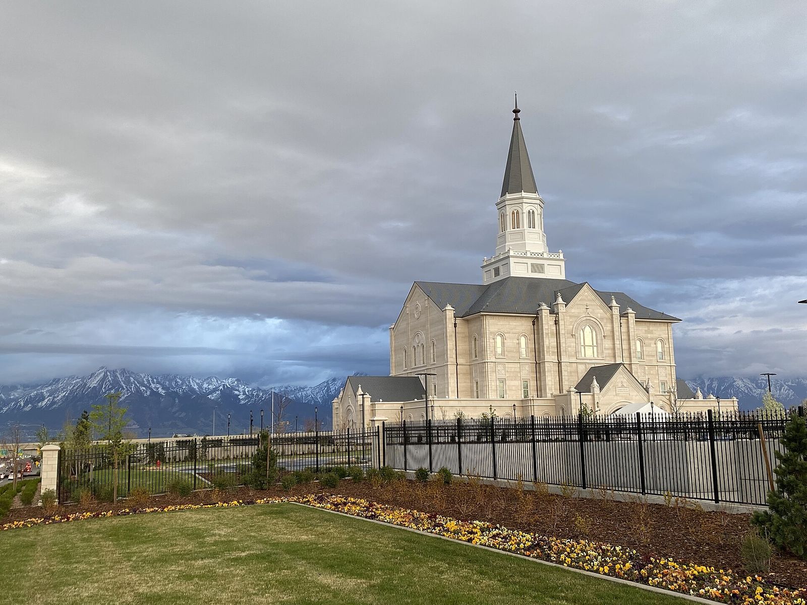 The Taylorsville Utah Temple during its open house, with a lawn in front and snowy mountains behind